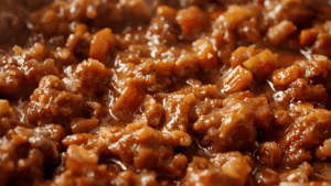 A close-up shot of thick, glossy Sloppy Joe mixture bubbling in a skillet.