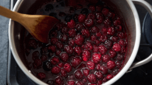 Once boiling, reduce the heat to low and let the berries simmer for about 10–15 minutes. Use a wooden spoon to mash the berries slightly as they soften — this helps release their juices and deep color.