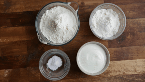 Ingredients for 4-ingredient bread: flour, baking powder, salt, yogurt on a wooden kitchen counter.