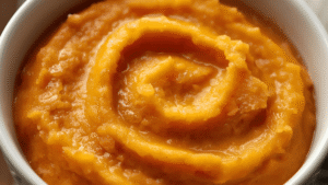A smooth orange bowl of mashed sweet potato, warm comforting tones.