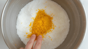 Add your granulated sugar to a large mixing bowl. Zest one large orange right over the top. Now, use your fingertips to rub the zest into the sugar. The grains will start to feel slightly damp and smell incredible. This tiny step makes a big difference. Instead of zest disappearing into the dough, every bit gets evenly distributed.