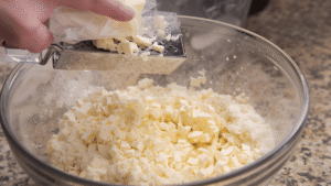 Take your frozen butter and grate it on the large holes of a cheese grater directly into the bowl of dry ingredients. Once all the butter is in, gently toss it with the flour so each little piece is coated. Don’t mash or overmix — you want those distinct bits of butter. This is what gives you that soft, tender texture and slightly crisp edge.