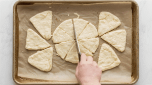 Using a sharp knife or bench scraper, slice the disc into 8 equal wedges (like slicing a pizza). Transfer each wedge to a baking sheet lined with parchment paper, leaving space between them so they can puff up and spread a bit. If your kitchen is warm and the butter seems like it’s starting to soften, you can slide the whole tray into the fridge for 15–20 minutes before baking. Chilled dough = better texture.